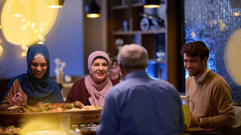 A modern and traditional European Islamic family comes together for iftar in a contemporary restaurant during the Ramadan fasting period, embodying cultural harmony and familial unity amidst a culinary celebration of diversity.